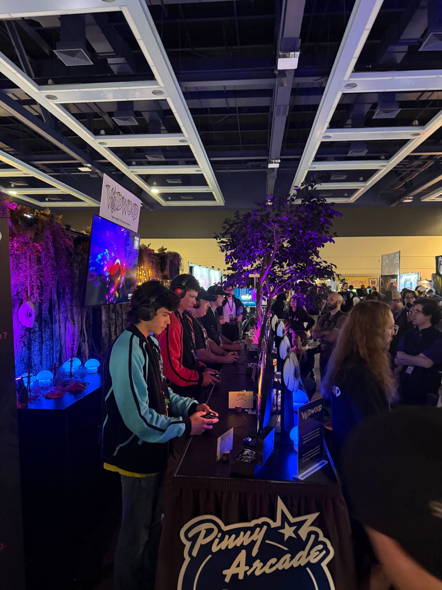 A row of players holding controllers at the Voidwood PAX West stations