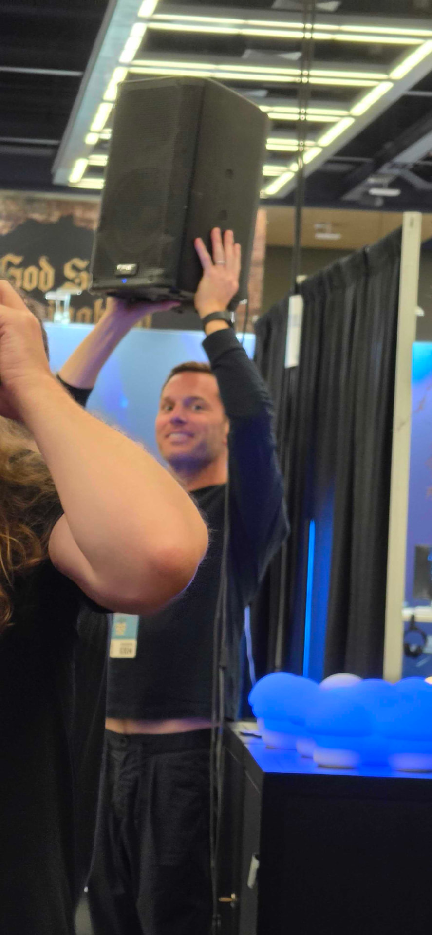 Voidwood founder Shawn Seibert holding a speaker above his head during booth setup